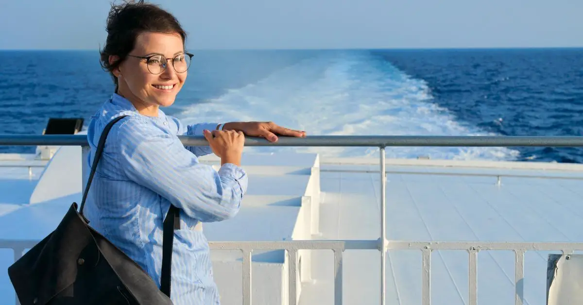 Middle aged woman at aft of cruise ship watching wake