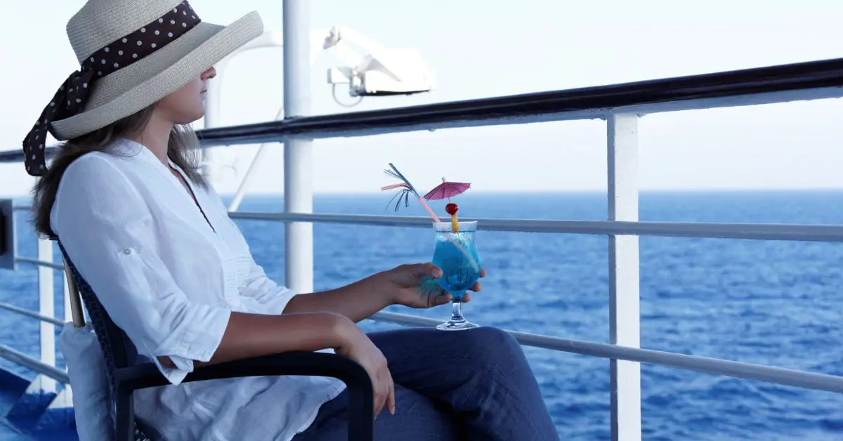 Single woman on cruise with cocktail overlooking ocean