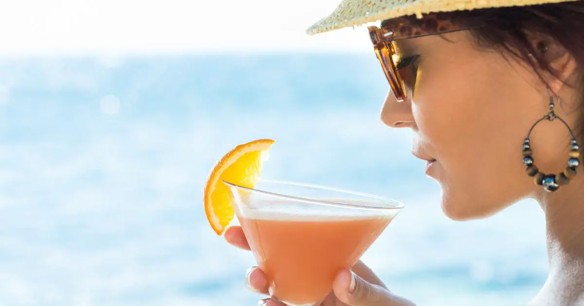 Young woman drinking cocktail at sea