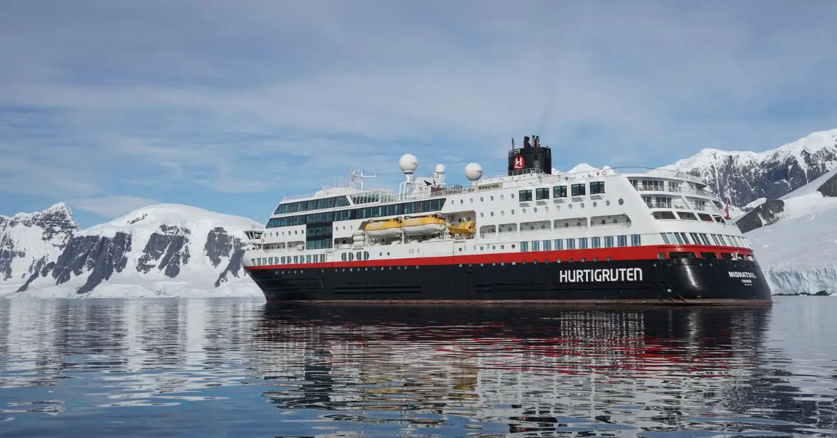 Hurtigruten sailing in Norway with snow topped mountains in the background