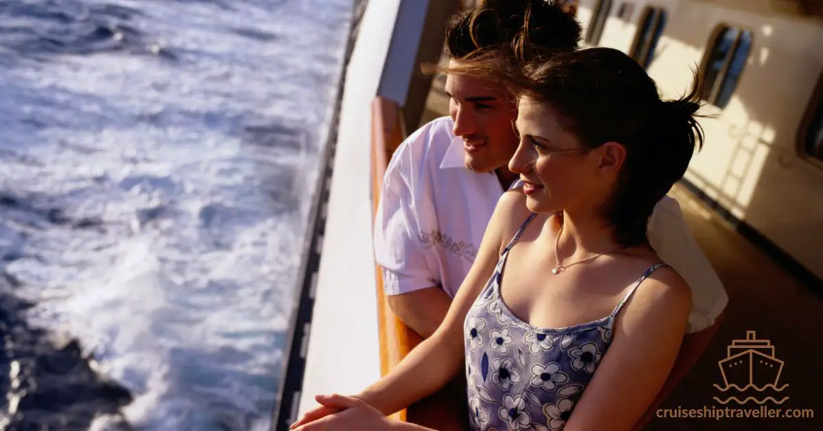 young couple overlooking side of cruise ship at sea